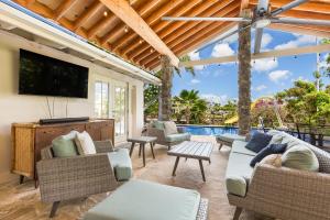 a patio with furniture and a tv and a pool at Tranquil Marina Front Pool House Resort in Honolulu