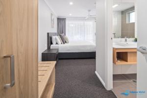 a bedroom with a bed and a bathroom with a sink at Hive Hotel, Moruya in Moruya