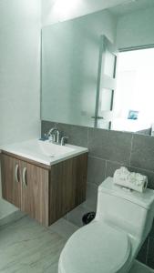 ein Badezimmer mit einem WC, einem Waschbecken und einem Spiegel in der Unterkunft The Views Resort in El Zonte