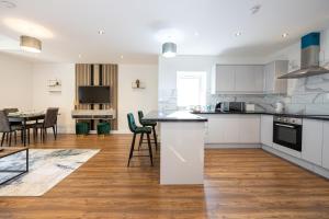 a kitchen with white cabinets and a table and chairs at Luxury 2 Bedroom Apartment In Chorlton in Manchester