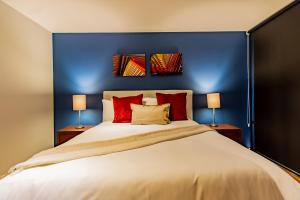 um quarto azul com uma cama grande e almofadas vermelhas em Capitalia - Luxury Apartments - Temístocles 40 em Cidade do México