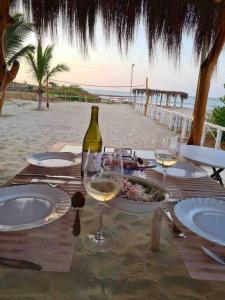 una mesa con un plato de comida y copas de vino en la playa en Casa Cárpena Playa Acapulco Zorritos, en Zorritos