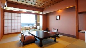 Habitación con mesa, sillas y vistas al océano. en Atagawa Yamatokan en Higashiizu