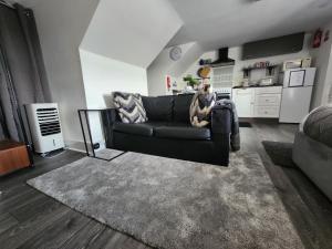 Quantock Loft Studio 3 في روتشستر: غرفة معيشة مع أريكة سوداء ومطبخ