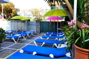 eine Gruppe blauer Stühle und Sonnenschirme auf einer Terrasse in der Unterkunft Hostal Magnolia in Lloret de Mar