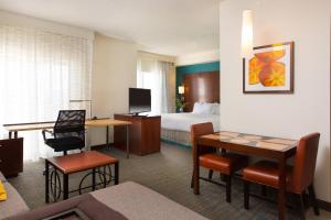 a hotel room with a bed and a desk and a table at Residence Inn Kansas City Airport in Kansas City