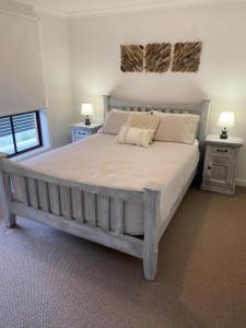 ein Schlafzimmer mit einem großen Bett mit zwei Tischen und zwei Lampen in der Unterkunft Ranges Over the Bay in Culburra Beach
