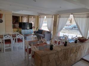 sala de estar con mesa, sillas y TV en Hotel Gran Lido en Santa Teresita