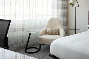 a bedroom with a chair next to a bed at Marriott Montreal Airport In-Terminal Hotel in Dorval