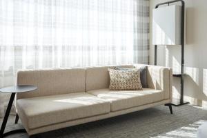 a couch in a living room with a window at Marriott Montreal Airport In-Terminal Hotel in Dorval