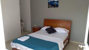 a bedroom with a bed with a wooden headboard at Hotel Los Estoraques in Aguachica