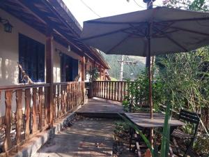 - une terrasse couverte en bois avec une table et un parasol dans l'établissement Casa 2 Cantina Florêncio São Pedro da Serra, à Nova Friburgo