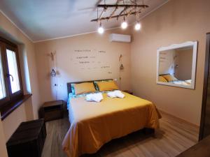 a bedroom with a bed with yellow sheets and a mirror at LA CASA DEL GRILLO - Valle del Menotre - Rasiglia in Orsano