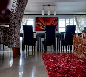 comedor con mesa, sillas y alfombra roja en Bhotani-on-Bax, en Port Elizabeth