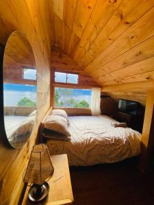 1 dormitorio en una cabaña de madera con 1 cama y 1 mesa en Cabaña en La Laguna de la Cocha, en Pasto
