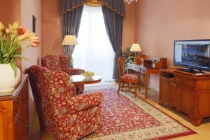ein Wohnzimmer mit einem Stuhl und einem TV in der Unterkunft Hotel Bristol in Karlsbad