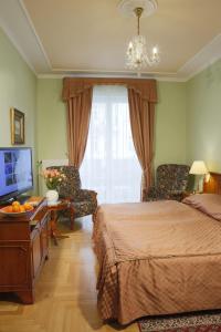 ein Schlafzimmer mit einem Bett, einem TV und einem Stuhl in der Unterkunft Hotel Bristol in Karlsbad