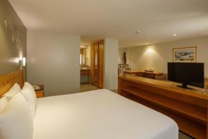 a bedroom with a white bed and a television at Cond Blue Tree Towers in Fortaleza