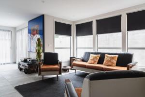sala de estar con 2 sofás, sillas y ventanas en Lavender Box en Dunedin