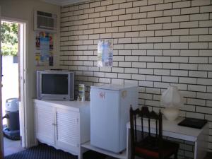 a kitchen with a refrigerator and a desk with a tv at Colonial Lodge Motel in Belmont