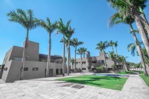 une villa avec des palmiers en face d'un bâtiment dans l'établissement Gales Park Hotel, à Dourados
