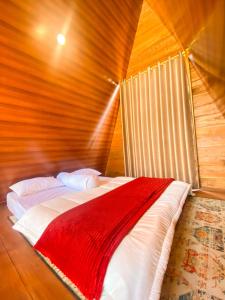 1 dormitorio con 1 cama con manta roja en Godieng Cabin, en Diyeng