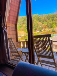 zwei Stühle auf einer Veranda mit Blick auf ein Fenster in der Unterkunft Godieng Cabin in Diyeng