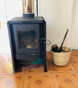 a black stove sitting on a wooden floor with a basket at Linda Casa en Carretera Austral in La Junta