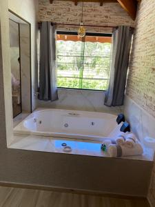 uma casa de banho com uma banheira e uma janela em Villagio da Mantiqueira em Monte Verde