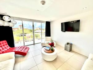 a living room with a red chair and a tv at Las Islas #12 in Palm-Eagle Beach