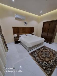 a bedroom with a large bed and a rug at أجنحة فندقية مفروشة عوائل فقط in Qal'at Bishah