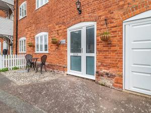 a brick building with two chairs and a table in front of a door at Coconut Mill in Lavenham
