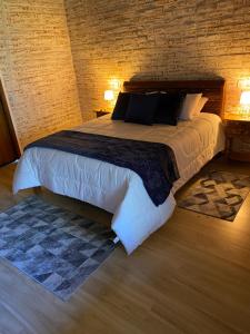 um quarto com uma cama grande com 2 candeeiros e uma parede de tijolos em Villagio da Mantiqueira em Monte Verde