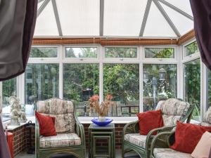 einen Wintergarten mit 2 Stühlen, einem Tisch und Fenstern in der Unterkunft Shiralee in Middle Winterslow
