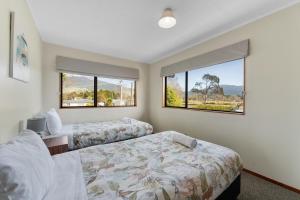 a bedroom with two beds and two windows at River Retreat, spa, pets, Wi-Fi in Turangi