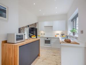 a kitchen with white appliances and a wooden floor at Yr Allt in Abergele