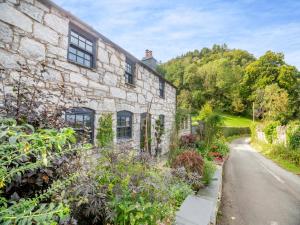 an old stone house with a garden next to a road at Yr Allt in Abergele