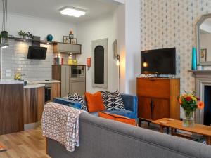George Apartment 54 في Whithorn: غرفة معيشة مع أريكة زرقاء ومطبخ