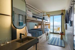 a room with a bunk bed and a sink and a mirror at Moxy Virginia Beach Oceanfront in Virginia Beach