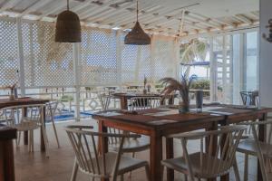 un restaurante con mesas y sillas de madera y ventanas en Hotel San Luis Beach House, en San Andrés