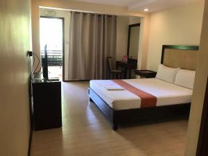 een slaapkamer met een bed, een bureau en een raam bij Subic Grand Seas Resort in Olongapo