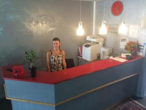 a woman standing behind a red and blue counter at Hôtel Restaurant Evan in Lempdes sur Allagnon