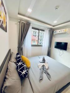 a small bedroom with a bed with a tv and pillows at Lovely Pool View Arcadia 1 bedroom condo in Pattaya South