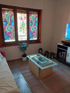 een woonkamer met een tafel en glas-in-loodramen bij MAILY Guest House in Alta Gracia