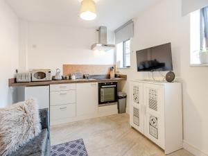 a kitchen with white cabinets and a tv on the wall at Molly Veroni - Uk43592 in Ellesmere