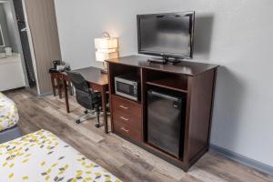 a hotel room with a desk and a television on a cabinet at Butler Inn in Oxford