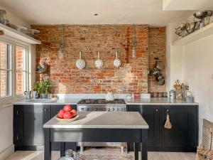 a kitchen with black cabinets and a brick wall at Campbell Cottage in Ticehurst