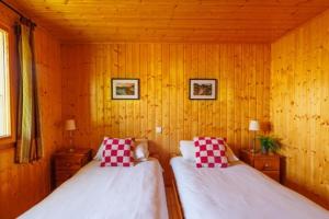 2 camas en una habitación con paredes de madera en Chalet Nicole, en La Côte dʼArbroz