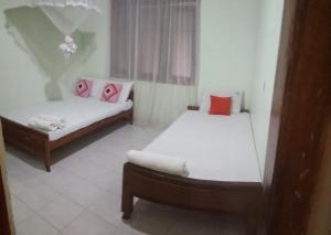 two twin beds in a room with a window at Osheen Family Guest House in Polonnaruwa