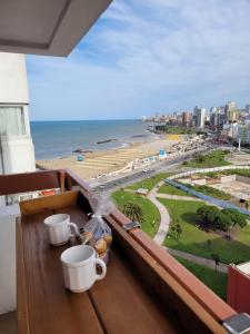 a balcony with two cups and a view of the beach at Nuevo estudio al mar con cochera in Mar del Plata